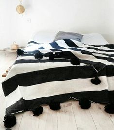 a black and white striped bed with pom poms