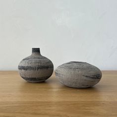 two gray vases sitting on top of a wooden table