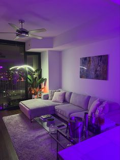 the living room is lit up with purple lighting and has a large sectional couch in front of it