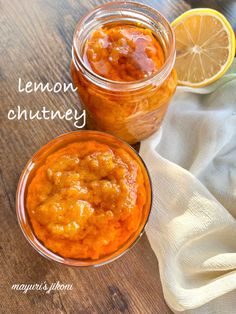 two jars of lemon chutney on a wooden table next to an orange slice