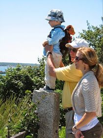 two women and a child are standing on a rock