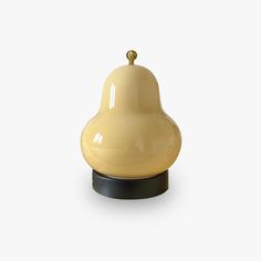 a yellow bell on a black stand against a white background, with the bell turned upside down