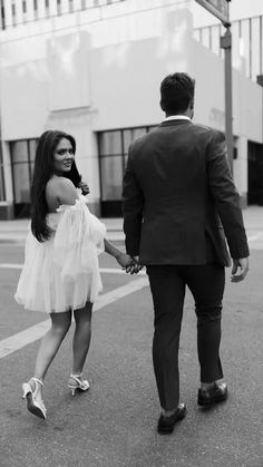 a man and woman walking down the street holding hands