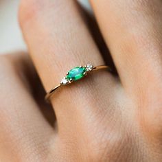 a woman's hand with a green ring on top of her finger and an emerald stone in the middle