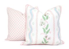 two white pillows with pink and green designs on them