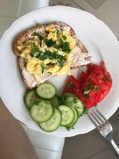 a white plate topped with toast, cucumbers and tomatoes