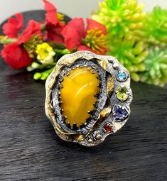 Baltic Amber Gemstone Ring in sterling silver with gold accents size 7 adjustable to bigger size Materials:  Silver 925, 24k Gold plated accents, Baltic Amber, Peridot, Garnet, Ioite, Blue Topaz Face of the ring:  Height - 35mm, Width-35mm, band - 9mm Unique Handcrafted One-of a-kind Design Ring Each Piece of Jewelry in my Collection is Absolutely One of a Kind! When you start wearing a piece of my jewelry you will fall in love with it more and more each day and feel that good Energy and Love th Unique Multi-stone Yellow Jewelry, Unique Yellow Multi-stone Jewelry, Yellow Gemstone Fusion Jewelry, Yellow Fusion Gemstone Jewelry, Yellow Fusion Style Gemstone Jewelry, Bohemian Yellow Round Rings, Artisan Jewelry With Gemstone Accents For Anniversary, Unique Multi-stone Citrine Rings, Unique Gemstone Accented Rings As Gift