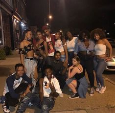 a group of people posing for a photo in front of a car on the street