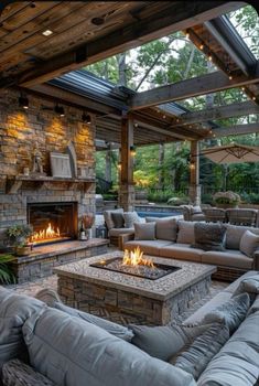 an outdoor living area with couches, tables and a fire place in the center