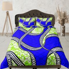 a bed with a blue and green comforter next to a lamp on a table