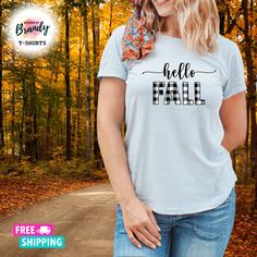 a woman wearing a t - shirt that says hello fall in front of trees and leaves