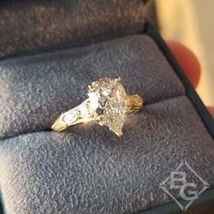 This stunning yellow gold vintage-style, diamond engagement ring by designer Gabriel will leave her speechless. This old-world beauty showcases a 1.72 carat pear cut lab-grown diamond center with 0.15 carats total accent round-cut diamonds in milgrain frames on either shoulder of an engraved knife edge band. The warm color of the yellow gold in the scroll detailing add to its exquisite beauty and enhances the warmness of the color in the center pear cut shown here (center stone sold separately).