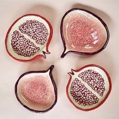 four red and white plates with designs on them sitting next to each other in the shape of pomegranates