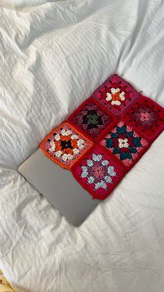 an open laptop computer sitting on top of a white bed covered in crochet