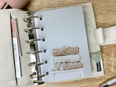 an open notebook with two knitted towels on it and a pen next to it