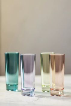 three different colored shot glasses sitting on top of a white counter next to each other