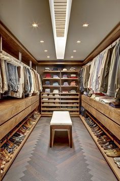 a walk - in closet with lots of clothes and shoes on the shelves, along with a bench