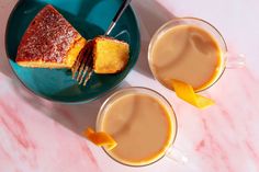 two cups of coffee with orange slices on the rim and cake in the mugs