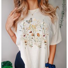 Relax and get cozy while wearing our cute new Cottagecore inspired Shirt!  It's got all the vibes including Boho, Wildflowers and Botanical.  This will make the perfect gift for yourself or any Nature Lover on your list.  ~ PRODUCT DETAILS ~ ❤ Comfort Colors brand ❤ 100 % Cotton ❤ Has a Vintage look and has a relaxed fit ❤ DTG (Direct to Garment) Printing. The Ink is printed directly into the fabric. There is no Vinyl used. ~ SIZING ~ ❤ Unisex Sizing ❤ Please refer to size guide in product image Spring Bohemian Crew Neck Tops, Cottagecore Printed T-shirt With Relaxed Fit, White Tops With Plant Print For Fall, Casual Fall Tops With Plant Print, Hippie Floral Embroidered Tops For Fall, Cute Cotton Tops With Floral Print, Cute Floral Print Tops For Fall, Fall Cottagecore Tops With Graphic Print, Cottagecore Graphic Print Tops For Fall