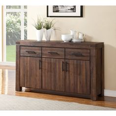 a wooden sideboard with two doors and three drawers in front of a large window