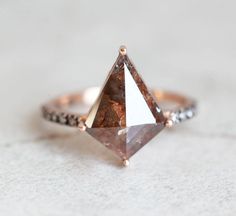 a ring with a brown and white diamond on it's side sitting on top of a table