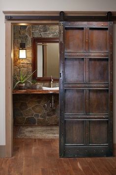 an open door leading to a bathroom with stone wall and wood flooring on the walls