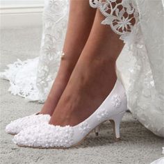 a close up of a woman's shoes on the ground with her wedding dress