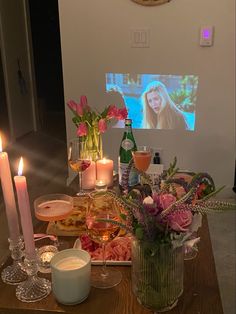 a wooden table topped with candles and vases filled with flowers next to wine glasses