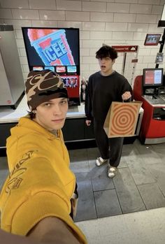 two young men standing in front of televisions