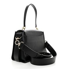 This is an authentic CHLOE Calfskin Small Tess Day Bag in Black. This stylish handbag is crafted of textured calfskin leather in black. It features a top handle and an adjustable leather shoulder strap. The bag includes polished silver and gold hardware including a decorative ring. The flap opens to a front pocket and beige fabric interior with a zipper pocket. Beige Fabric, Day Bag, Silver And Gold, Gold Hardware, Front Pocket, Top Handle, Zipper Pocket, Calf Skin, Chloe