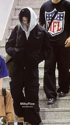 a man in black is walking down the stairs with an umbrella over his head and two other men are standing behind him