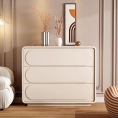 a white dresser sitting in a living room next to a chair and vase on top of it