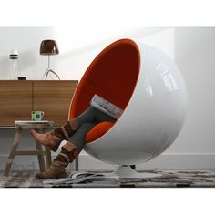 a woman sitting in an egg chair with her feet up on the table next to it