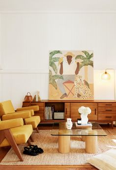 a living room filled with furniture and a painting on the wall above it's coffee table