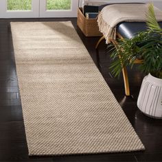 a large rug in the middle of a living room next to a chair and potted plant