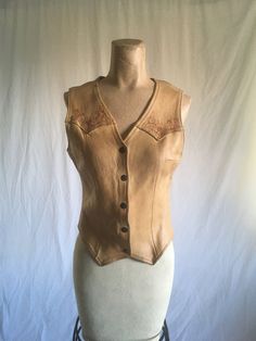 "vintage 1970s women's leather vest color most like mannequin pictures kind of a wheat color custom burn art snap up front straight back hem front hem-double chevron chevron chest burn art on upper chest and lower back good vintage condition, authentic age wear-rusty snaps (work), aged patina w/marks/scuffs, has a bit of a musty smell measures, lying flat, shoulder-13\" chest-16 1/2\" waist-14\" hem-14\" length-20 1/2\" back length-17 3/4\"" Fitted Biker Vest For Fall, Brown Sleeveless Vest For Western-themed Events, Fitted Leather Festival Vest, Vintage Fitted Vest For Fall, Fitted Biker Vest For Festivals, Biker Style Fitted Vest For Festivals, Fitted Western Leather Vest, Fitted Retro Vest For Festivals, Vintage Fitted Leather Vest