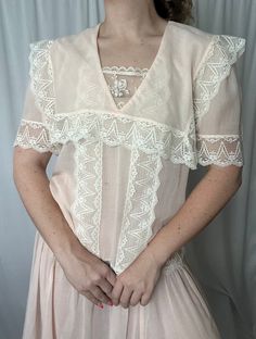 Details: maxi length; not lined, semi-sheer; white lace detail around hemline, waist, bust, neckline and sleeves; v-neckline with lace panel detail; cape/bib overlay detail; no zip closure.  Damage: small blemish to front right hand side of skirt (not noticeable) otherwise no clear damage, excellent vintage condition.  Shoulders: 15 in // Bust: 42 in // Waist (dropped): 40 in // Sleeves: 11.5 in // Overall Length: 52 in Please note all inventory is pre-loved and sold as is. I will always do my a Feminine V-neck Delicate Lace Top, White V-neck Lace Top With Lace Sleeves, V-neck Lace Top For Wedding, Delicate Lace V-neck Top, Feminine Lace Top With V-neck And Lace Collar, Feminine V-neck Lace Top With Lace Collar, Spring V-neck Lace Top With Lace Trim, White Feminine Lace Top With Lace Trim, Fitted V-neck Lace Top With Lace Collar