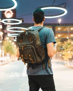 a man walking down the street with a backpack on his back and lights in the background