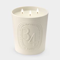 a white candle holder with three lit candles in the shape of a number 34 on it