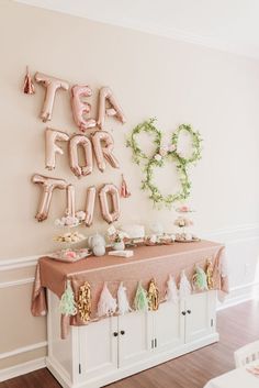 a table with balloons and decorations on it in front of a wall that says tea for two