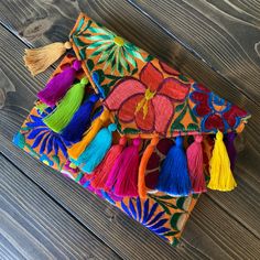 multicolored embroidered clutch bag with tassels on wooden floor next to wall