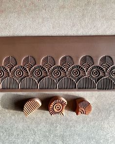 three cookies sitting on top of a table next to a chocolate tray with carved designs