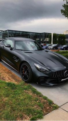 a black mercedes sports car parked on the side of a road in front of a building