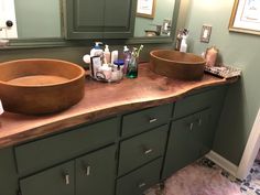 two sinks in a bathroom with green cabinets and mirrors on the wall above them are soaps, toothbrushes, and lotion