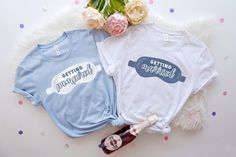 two t - shirts with the words getting married and getting married on them next to flowers