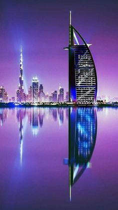 the burj dubai skyline is lit up at night with its reflection in the water