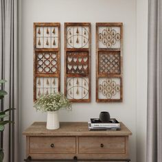 two wooden wall hangings above a dresser in a room with curtains and a plant