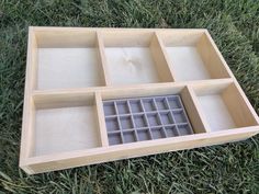 a wooden box filled with compartments on top of grass