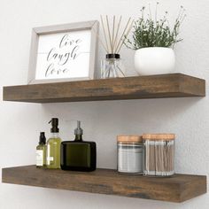 two wooden shelves with soap, lotion and candles on them in front of a white wall