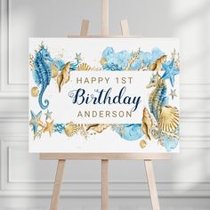 an easel with a happy 1st birthday card on it and seashells around the frame